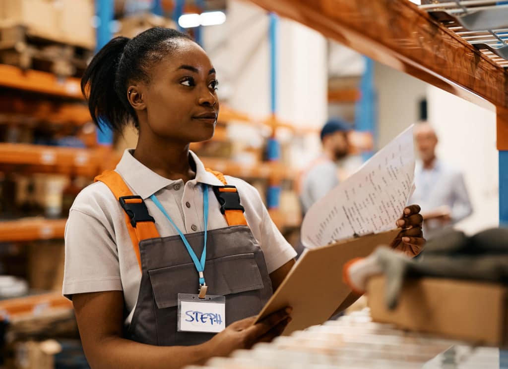 Warehouse worker going through checklist at storage compartment